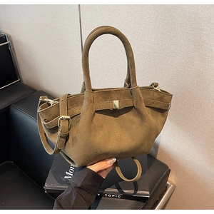 Detailaufnahme der braunen Handtasche aus mattem Leder mit Metallschnalle und Schultergurt