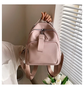 Detail of light pink PU leather backpack featuring sturdy top handle and matching shoulder strap