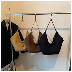 Detailed close-up of suede tote bags in camel, dark brown, and black on a metal rack