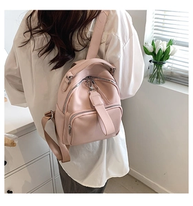 Pink mini backpack in lychee-pattern faux leather being worn by a female model