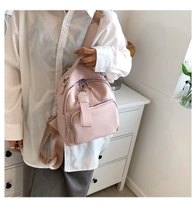 Detail of pink pebbled leather mini backpack with silver zippers and webbing straps