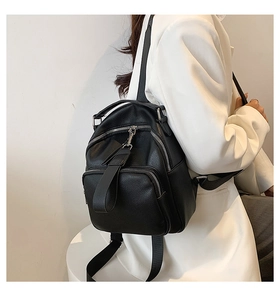 Mini black pebble leather backpack for women with silver zippers and white blazer contrast