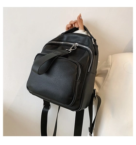 Detail of black pebbled PU leather backpack with silver zippers and adjustable straps
