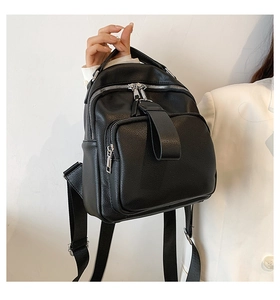 Detailed close-up of a black lychee-textured leather backpack with silver zippers