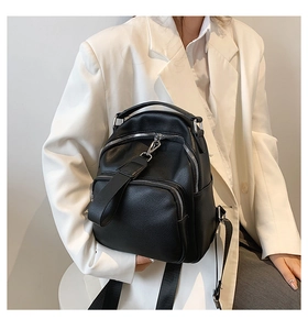 Close-up of black pebble leather backpack with silver zippers on a white blazer model