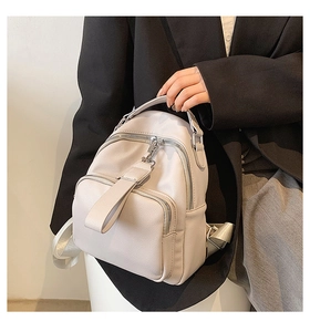 Close-up of a mini light gray faux leather backpack with litchi texture and silver zippers