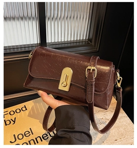 Détail du sac à bandoulière vintage en cuir verni marron avec fermoir rotatif doré en métal