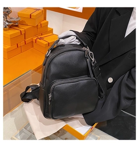 Detail of black pebbled leather mini backpack with metal zippers on orange display