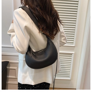 Close-up of black crescent hobo bag with pebble leather texture and gold zipper detail