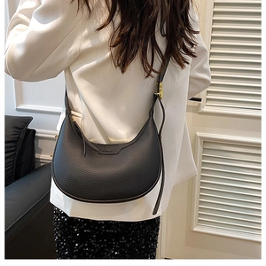 Detail of adjustable gold buckle and pebble leather texture on black crescent bag