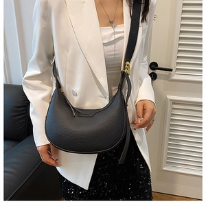 Detail of black litchi leather half-moon bag with embossed logo and gold buckle