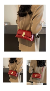 Détail du sac à main rouge en cuir ciré avec fermoir doré porté sur un blazer beige