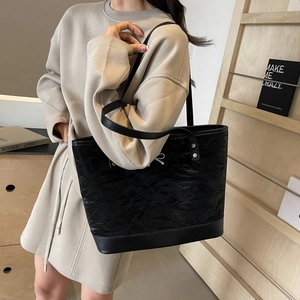 Grand sac cabas noir froissé avec nœud argenté porté par un mannequin en intérieur