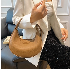 Brown grainy leather crescent hobo bag shown as a shoulder carry style on a model