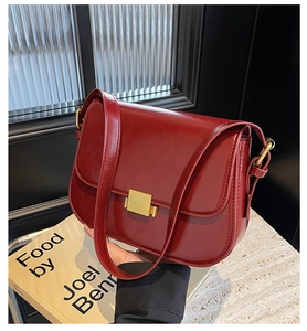 Close-up of vintage burgundy crossbody bag with golden buckle and textured leather finish