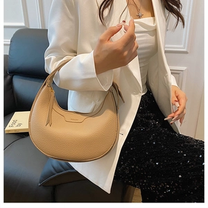Detail of apricot pebbled leather half-moon bag worn with elegant blazer and trousers