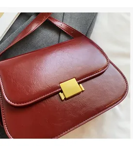 Detailed macro view of luxury burgundy glossy leather with a golden metallic square buckle
