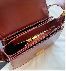 Detail view of deep red glossy leather handbag featuring triple-layer interior and gold zipper
