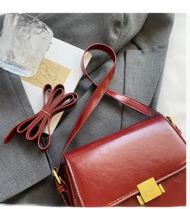 Macro view of vintage wine red crossbody bag with golden metal buckle on grey suit fabric