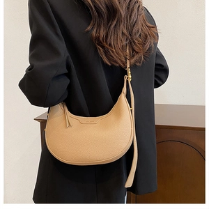 Detail of light beige pebbled leather hobo bag with gold hardware and brand embossing