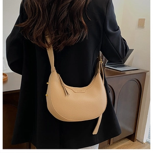 Close-up of light brown lychee grain leather saddle bag on a model's shoulder