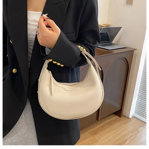 Detail of off-white crescent handbag with lychee texture and gold metal ring hardware