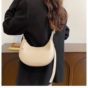 Chic beige lychee leather crescent hobo bag with gold hardware shown on a model