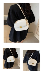 Detailed view of cream saddle bag with golden square metal buckle on leather flap