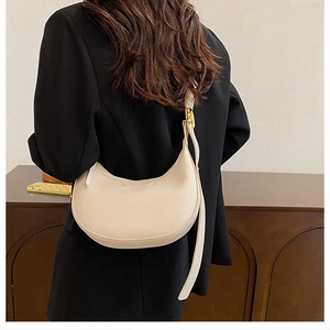 Close-up of beige moon bag with lychee grain texture and gold metal buckle detail