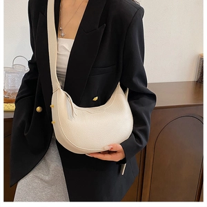 Model wearing a minimalist cream half-moon hobo bag with pebbled leather texture