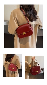 Close-up of red glossy leather shoulder bag featuring a gold rectangular metal clasp