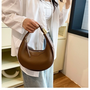 Detailed close-up of brown litchi pattern leather and gold buckle on the crescent bag