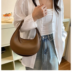 Detail of premium brown lychee texture leather on a stylish crescent underarm bag