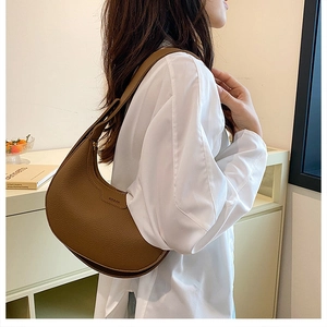 Detail shot of brown lychee texture hobo bag worn by model showing side profile and logo
