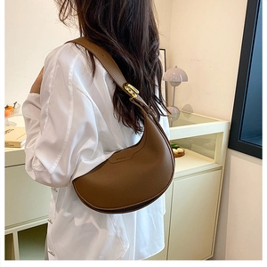 Close-up of brown pebbled leather shoulder bag with gold hardware and brand logo detail