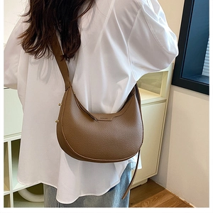 Detailed back view of a brown pebbled leather crescent hobo bag with gold metal studs