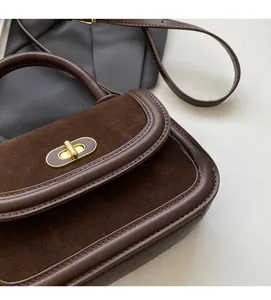 Close-up of retro brown patchwork handbag showing leather texture and gold oval twist lock