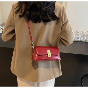 Détail du sac à bandoulière en cuir rouge vintage avec un fermoir doré élégant et chic