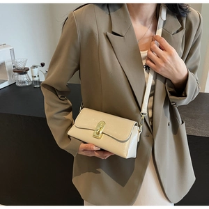 Détail du sac baguette blanc crème brillant avec fermoir rotatif doré sur modèle