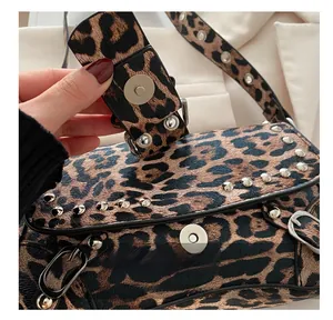Gros plan du rabat du sac léopard avec clous argentés et boucle magnétique métallique