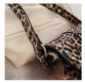 Détail d'un sac léopard avec des clous métalliques argentés et une bandoulière à œillets
