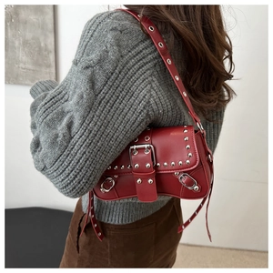 Détail du sac sous le bras en cuir rouge foncé avec rivets argentés et boucles