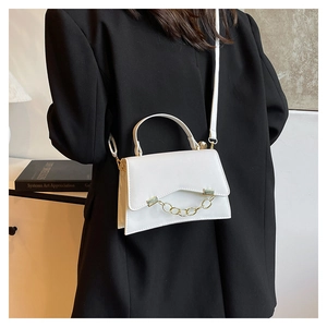 Detailed close-up of a white textured crossbody bag with gold chain and wavy flap edge