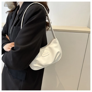 Detail of the white pleated PU leather crescent bag featuring an oval fashion logo patch
