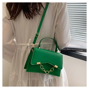 Detail shot of a green leather box bag with a golden chain and V-shaped flap design