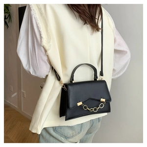 Rear view of model wearing a black leather box bag with gold chain and shoulder strap