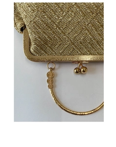 Détail d'un sac shell tressé vintage doré avec poignée anneau en métal et accents floraux