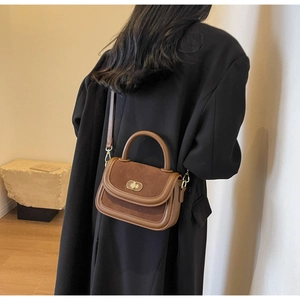 Detail view of a vintage brown matte crossbody bag worn by a model in a minimal setting