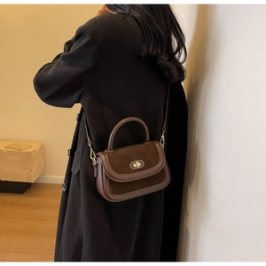 Detail of vintage matte brown leather handbag with gold metal clasp and stitching