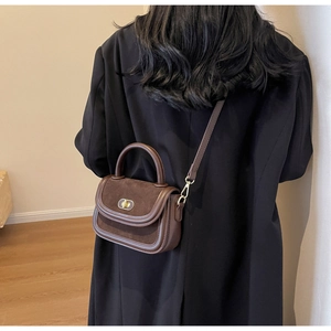 Detail of vintage dark brown faux suede handbag with gold oval twist lock and top handle